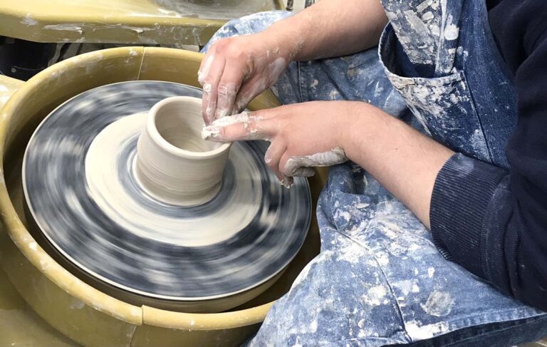 hands throwing pot on wheel