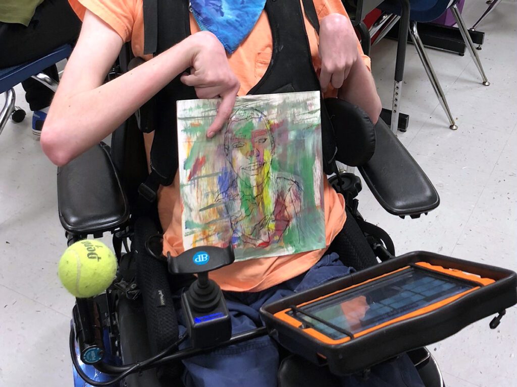 student holding artwork wheelchair